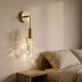 Gold Hook Hanging Glass Rock LED Wall Light beside a bed