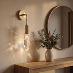 Gold hook hanging glass rock wall light beside a round mirror in an entry hall