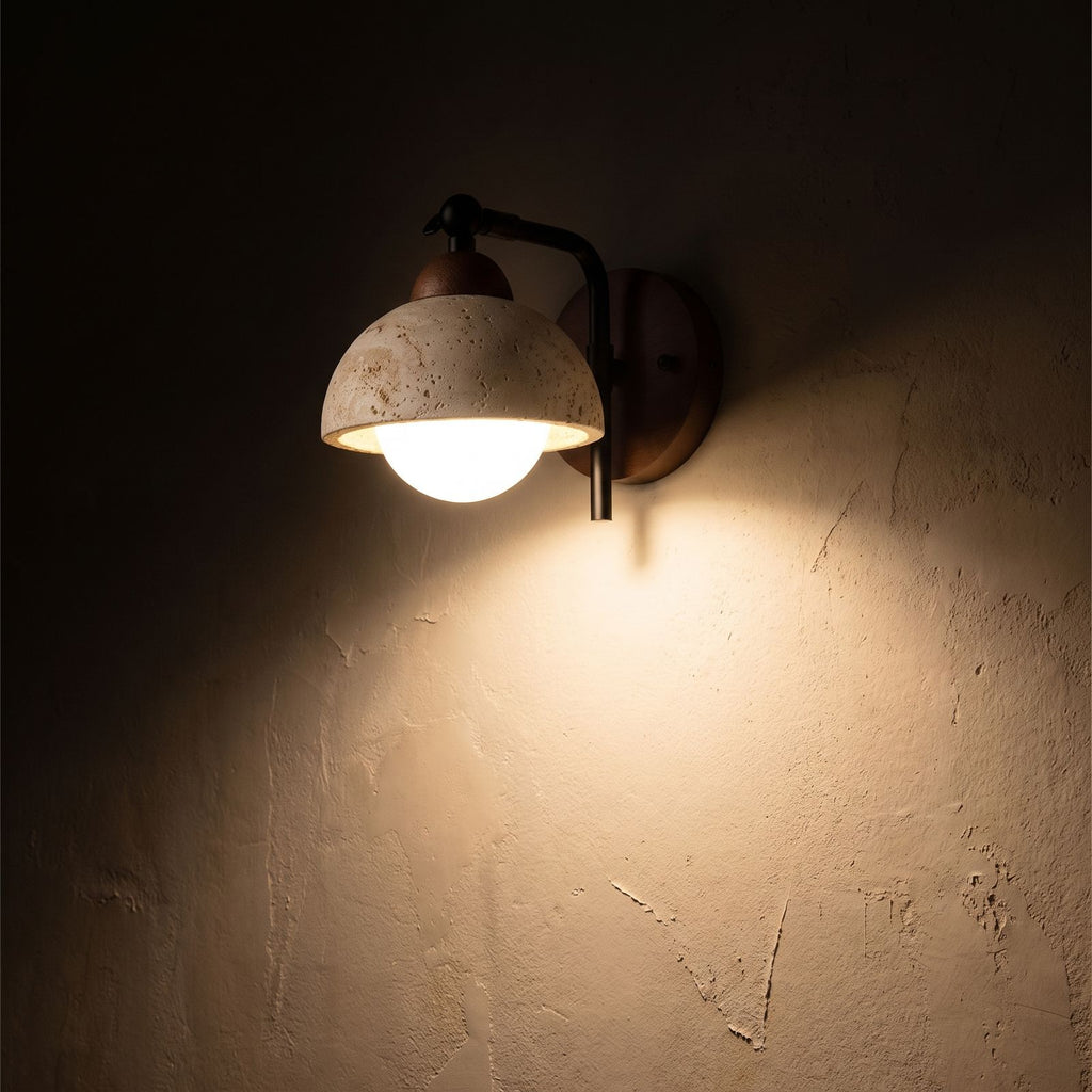 Gooseneck Travertine Dome and Globe Wall Light glowing on a plaster wall at night