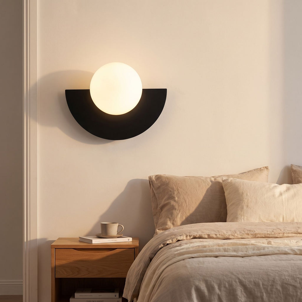 Half Moon Iron and Opal Globe Wall Light beside a bed