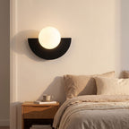 Half Moon Iron and Opal Globe Wall Light beside a bed