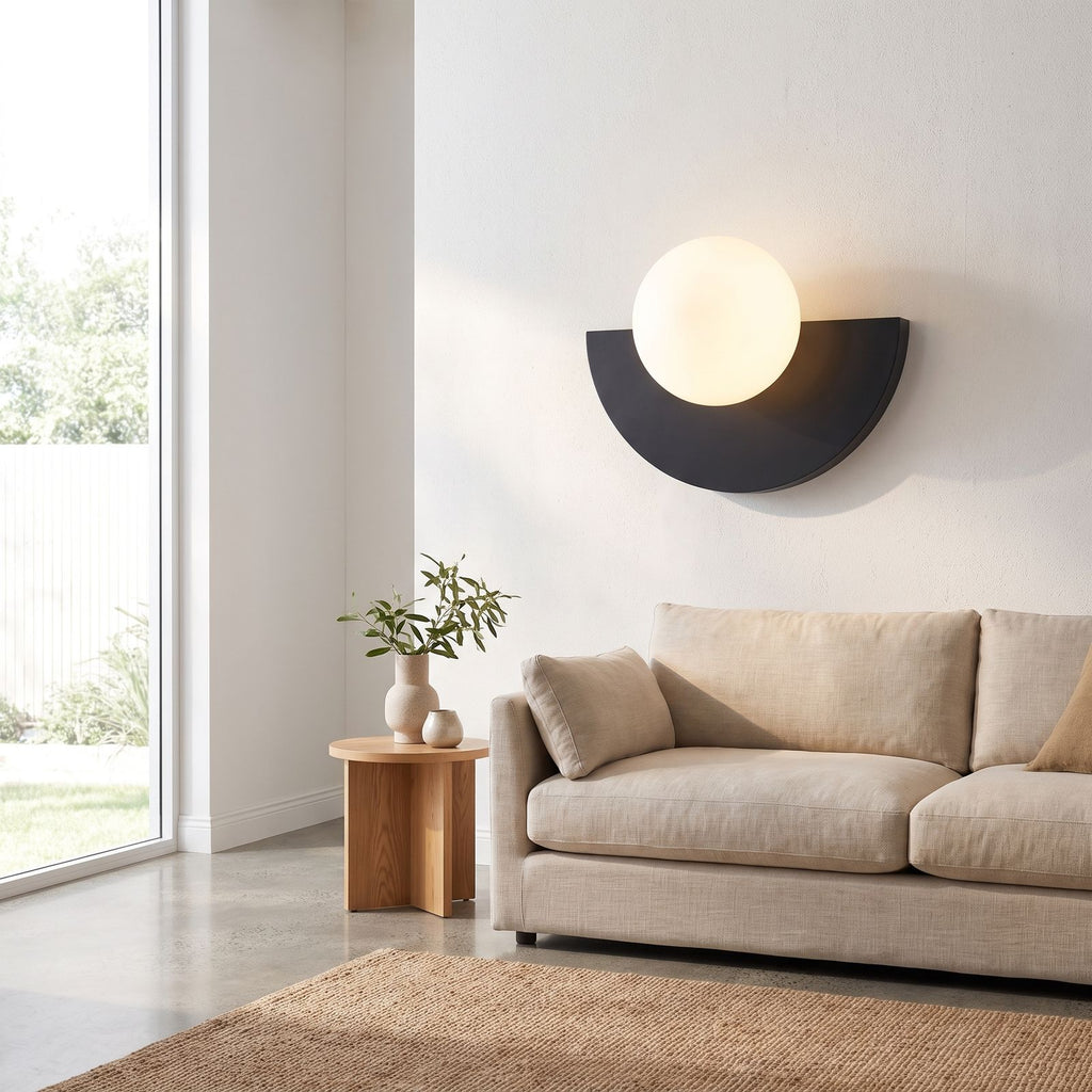 Half moon iron and opal globe wall light beside a living room sofa in daylight
