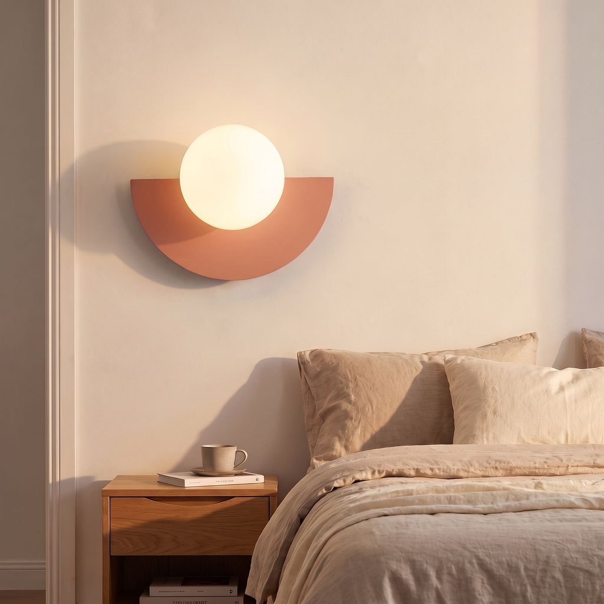 Half Moon Iron and Opal Globe Wall Light in pink beside a bed