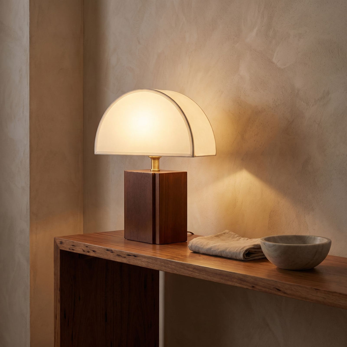 Half Moon Shade Bamboo Base Table Lamp glowing on a timber console at dusk