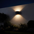 Half Round Up Down Outdoor Wall Light glowing on a garden wall at night
