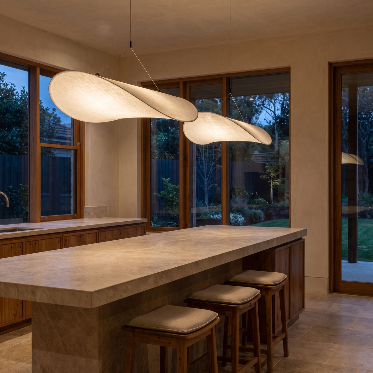 A pair of Hand-Knitted Silk Fabric Pendant Lights over a stone kitchen island