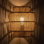 Hand Woven Natural Fibre Up Down Wall Light glowing on a plaster wall at night