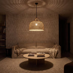 Handwoven Rattan Japandi Pendant Light at night casting woven shadows over a living room