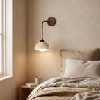 Hanging Travertine Shade LED Wall Light on a bedroom wall beside the bed
