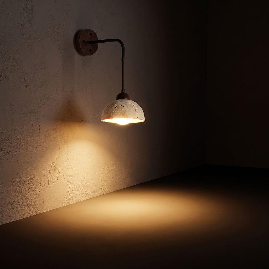 Hanging Travertine Shade LED Wall Light glowing on a plaster wall at night