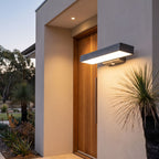 Horizontal Flat Bar Stainless Steel LED Outdoor Wall Light beside a timber front door at dusk