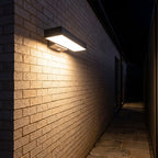 Horizontal flat bar outdoor wall light along a side passage at night
