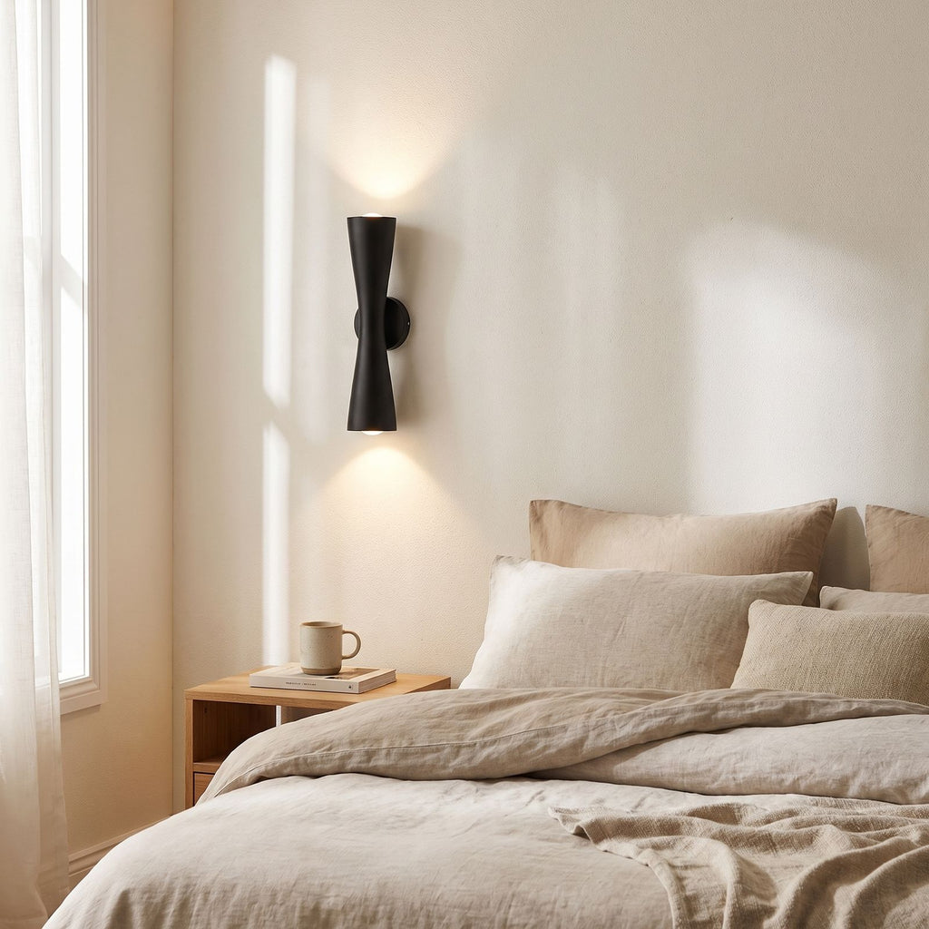 Hourglass Aluminium Up Down Wall Light on a bedroom wall beside the bed