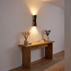 Hourglass Aluminium Up Down Wall Light in a hallway above a timber console