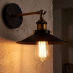 Industrial Saucer Shade Iron Wall Light glowing on a plaster wall at night