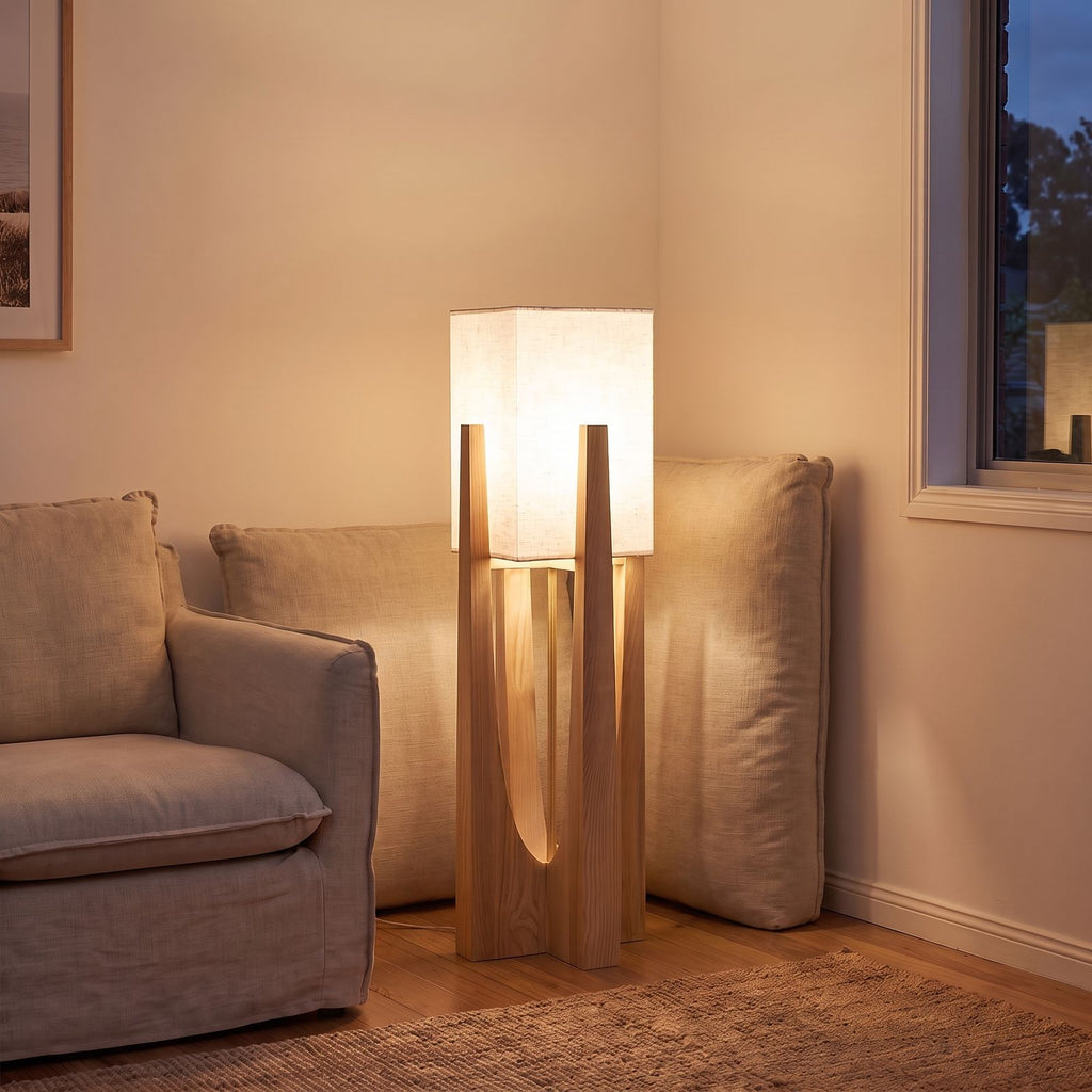 Wood frame fabric shade floor lamp at the end of a sofa at night