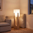 Wood frame fabric shade floor lamp at the end of a sofa at night