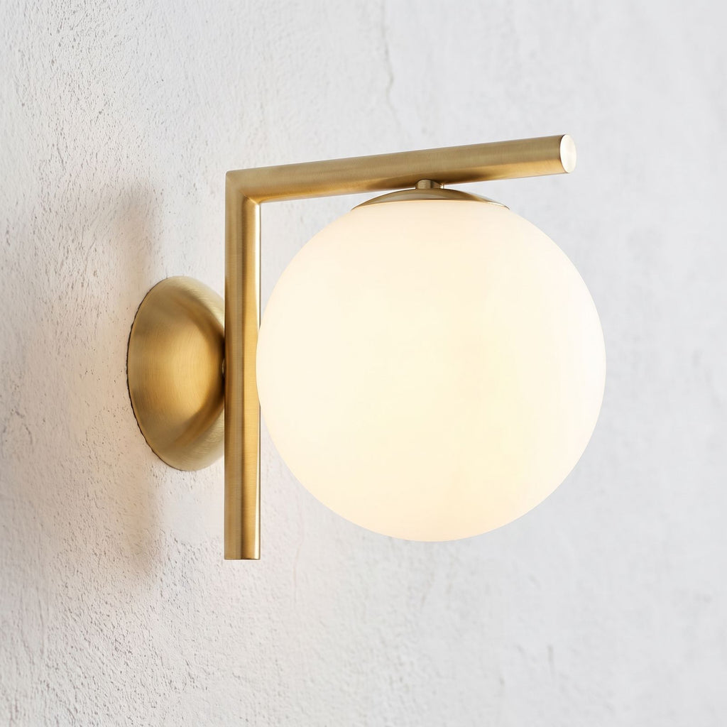 L-Arm Brass and White Glass Globe Wall Light, close view at 45 degrees on a plaster wall