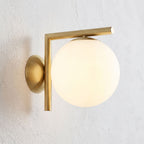 L-Arm Brass and White Glass Globe Wall Light, close view at 45 degrees on a plaster wall