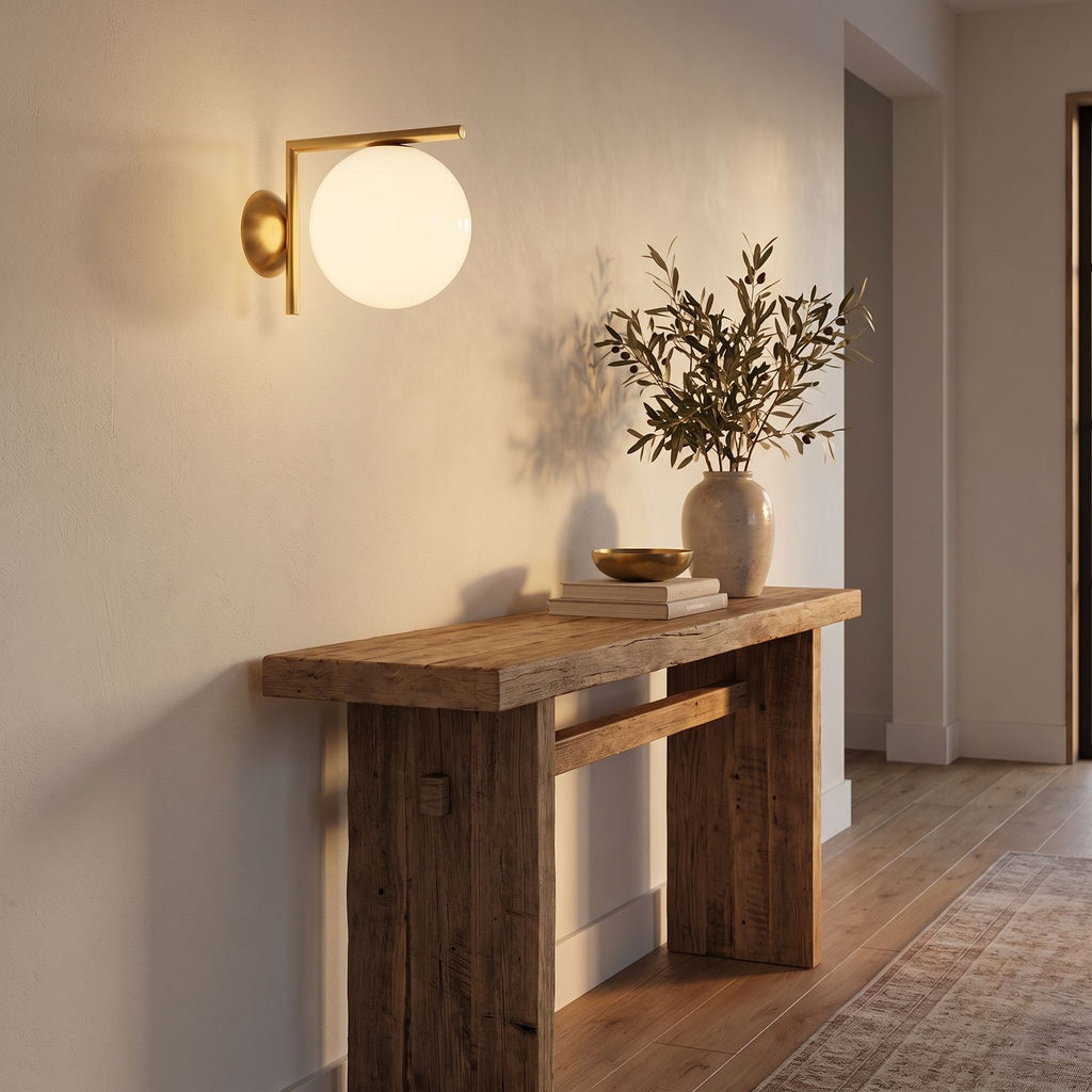 L-Arm Brass and White Glass Globe Wall Light in a hallway above a timber console