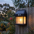 Lantern Shape Filament LED Solar Sensor Wall Light on a timber fence at dusk