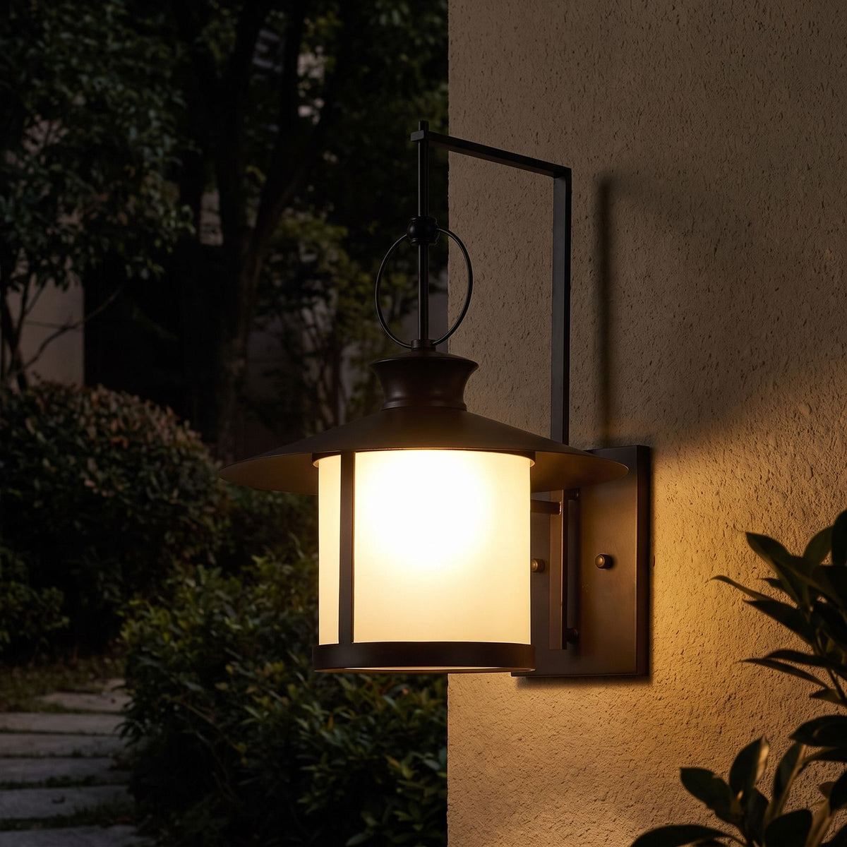 Large Black Iron Lantern Outdoor Wall Light glowing on a garden wall at night