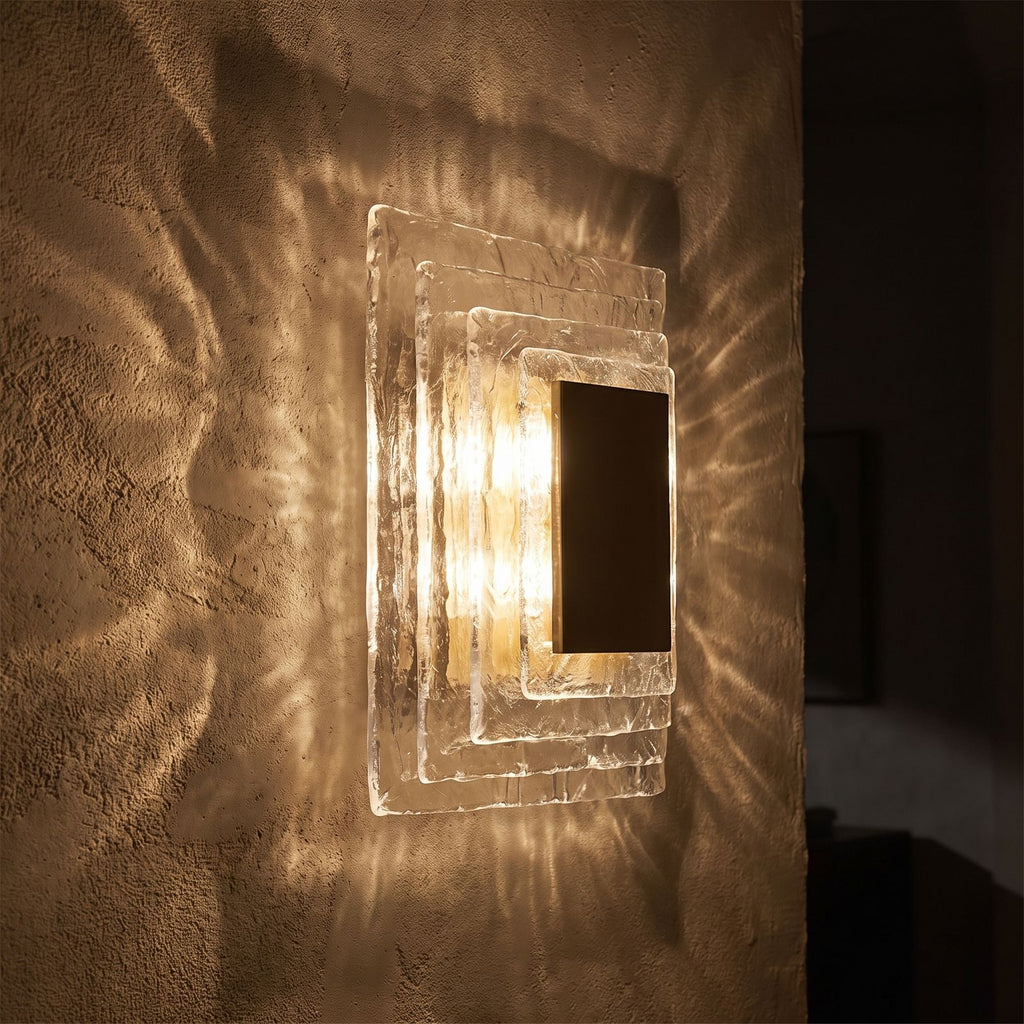 Layered Water Ripple Glass Panel Wall Light glowing on a plaster wall at night