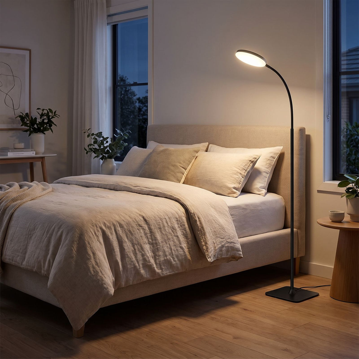 Black gooseneck reading floor lamp beside a bed in a bedroom at night