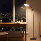 Gooseneck floor lamp over a desk in an apartment home office at night