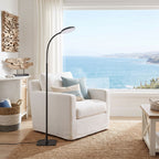 Gooseneck floor lamp beside a linen armchair in a coastal living room