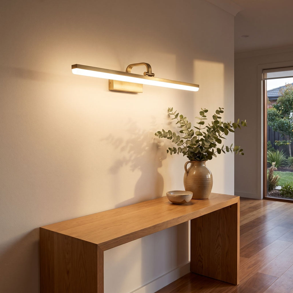 Linear brushed brass LED wall light above an entry console