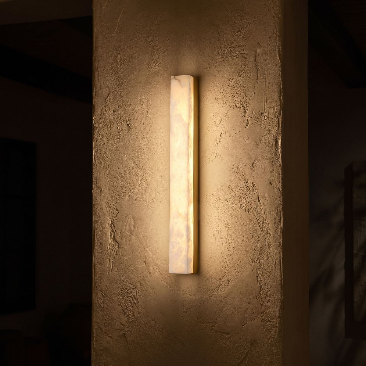 Long Alabaster Bar LED Wall Light glowing on a plaster wall at night