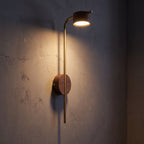 Long Rod Wood Bedside Reading Wall Light glowing on a plaster wall at night