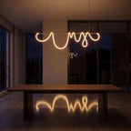 Looped LED rope linear pendant light over a dining table at night