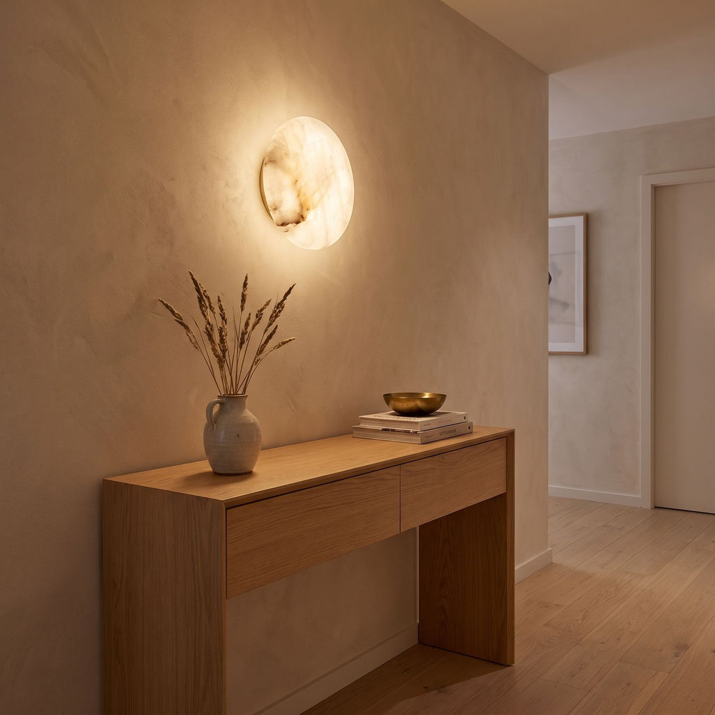 Low-Profile Round Alabaster LED Wall Light in a hallway above a timber console