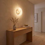 Low-Profile Round Alabaster LED Wall Light in a hallway above a timber console