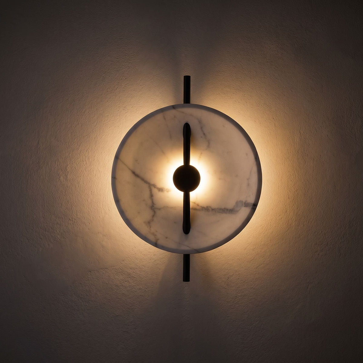Marble Disc and Black Bar Wall Light glowing on a plaster wall at night