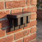 Matte Black Metal Outdoor Wall Light, close view at 45 degrees on a stone wall