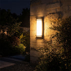 Metal and Acrylic Courtyard Outdoor Wall Light glowing on a garden wall at night