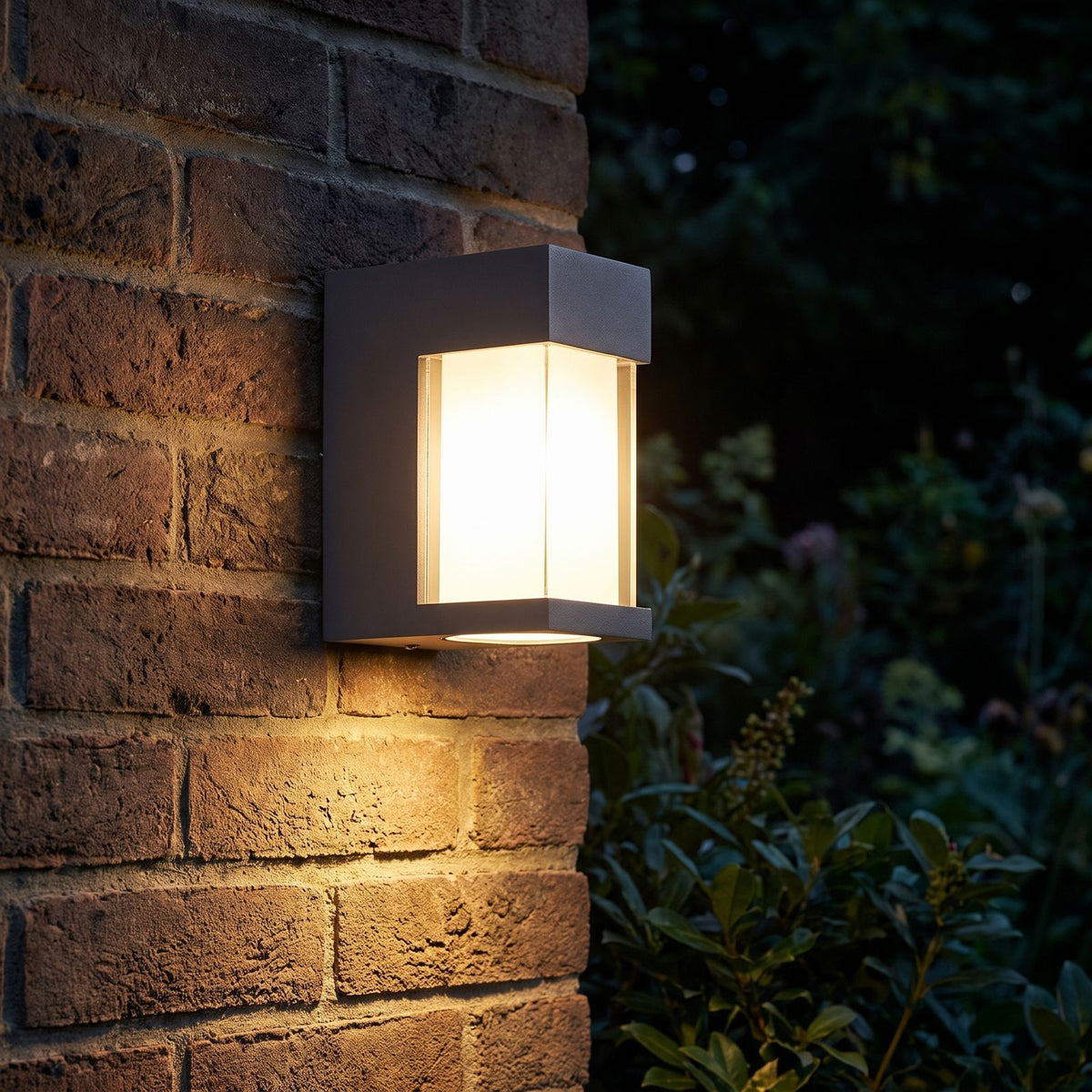 Metal and Glass GU10 Outdoor Wall Light glowing on a garden wall at night