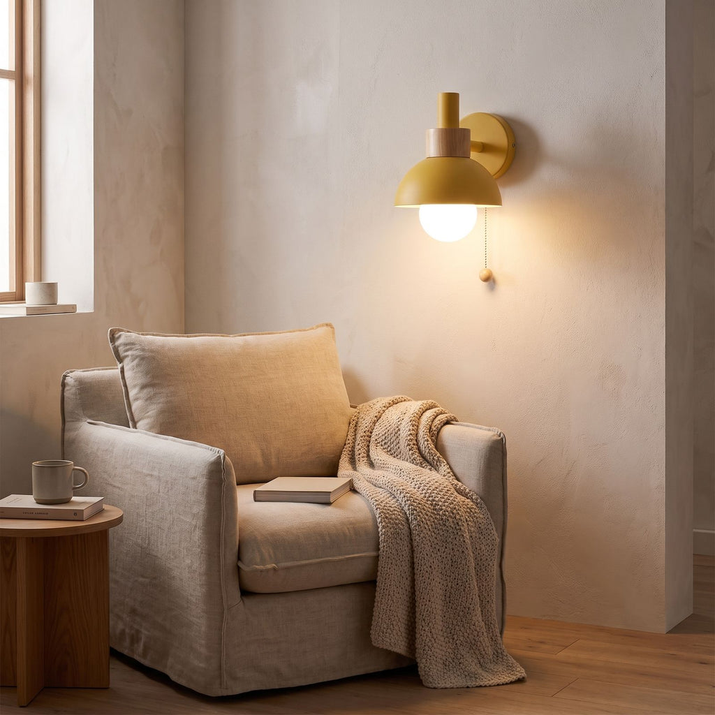Metal dome pull chain wall light above an armchair in a reading corner