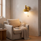 Metal dome pull chain wall light above an armchair in a reading corner