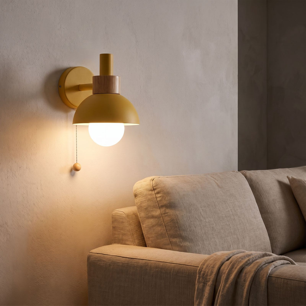 Metal dome pull chain wall light beside a living room sofa at night