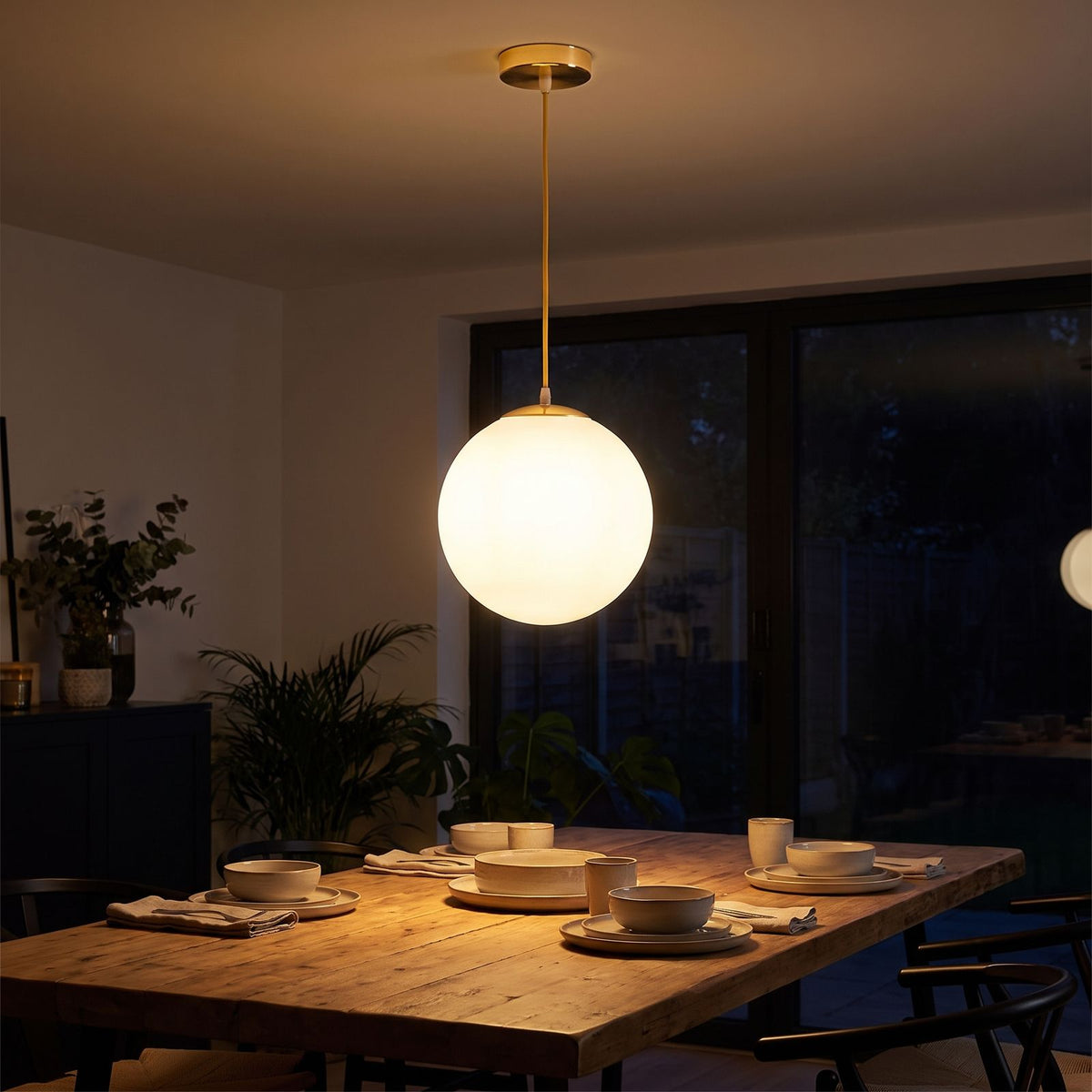 Milky Glass Globe Pendant Light above a dining table at night