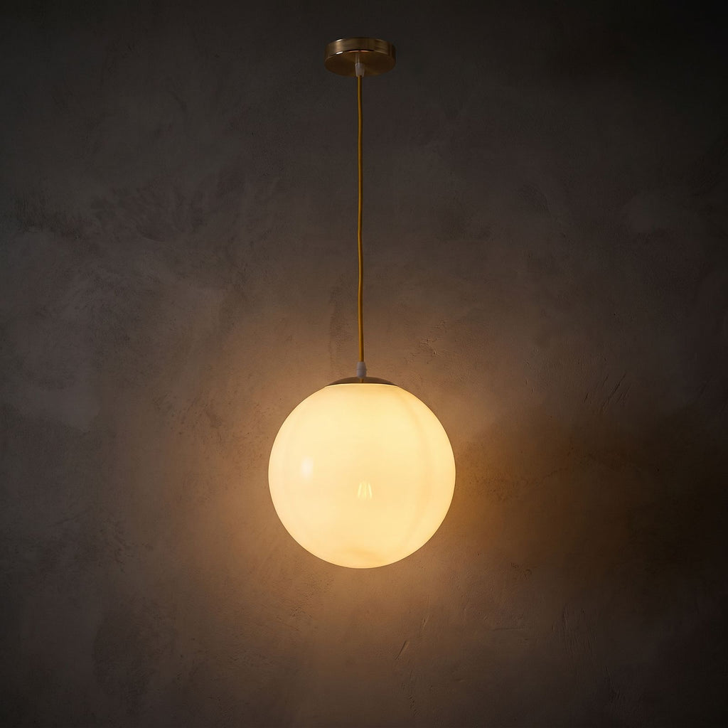Milky Glass Globe Pendant Light glowing against a plaster wall at night
