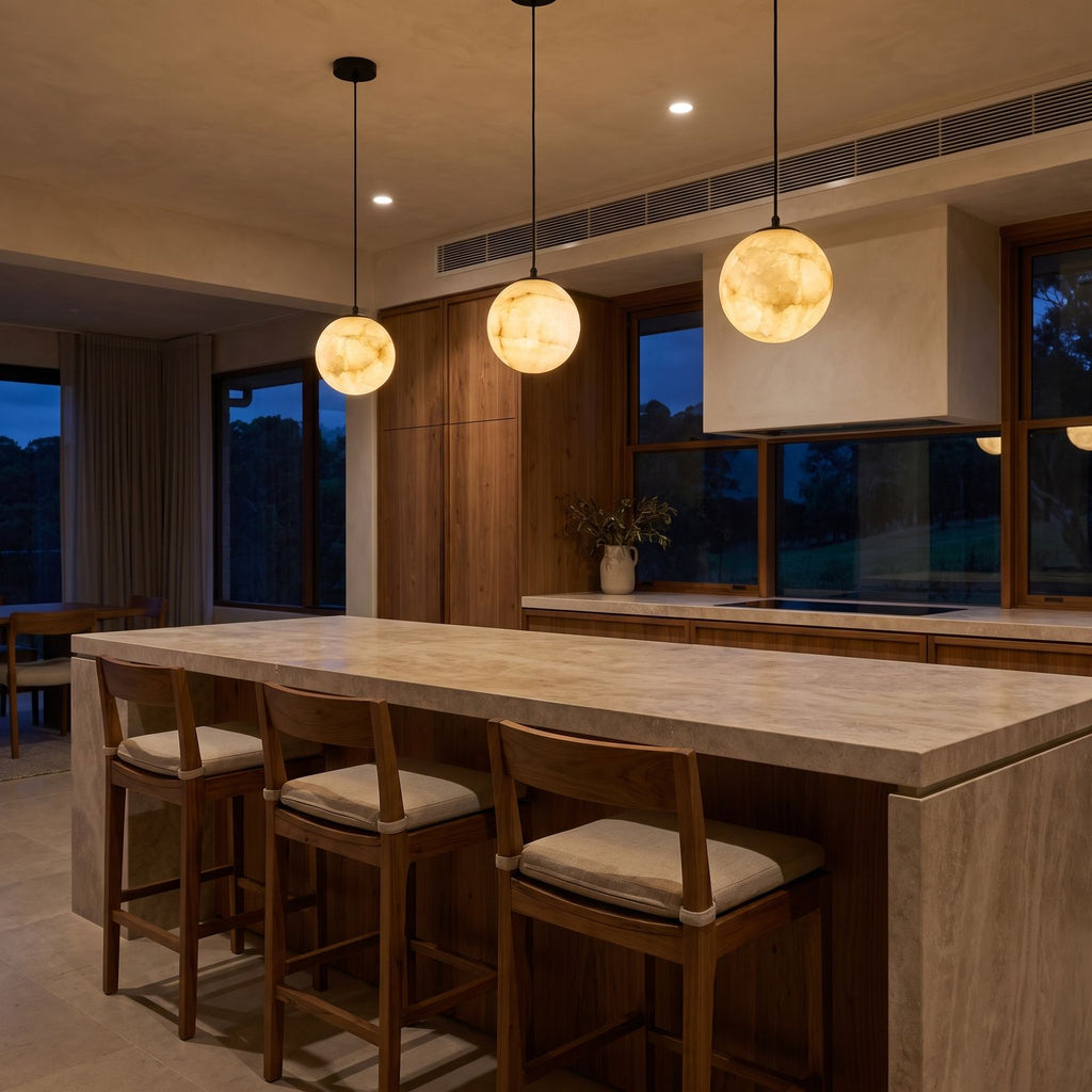 A row of three Mini Alabaster Globe LED Pendant Lights over a stone kitchen island