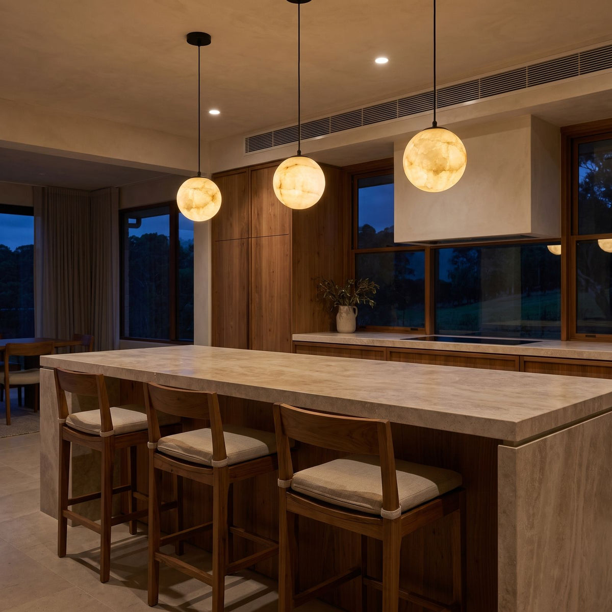A row of three Mini Alabaster Globe LED Pendant Lights over a stone kitchen island