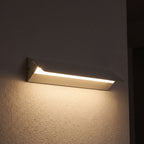 Minimalist White Metal Bar LED Wall Light glowing on a plaster wall at night