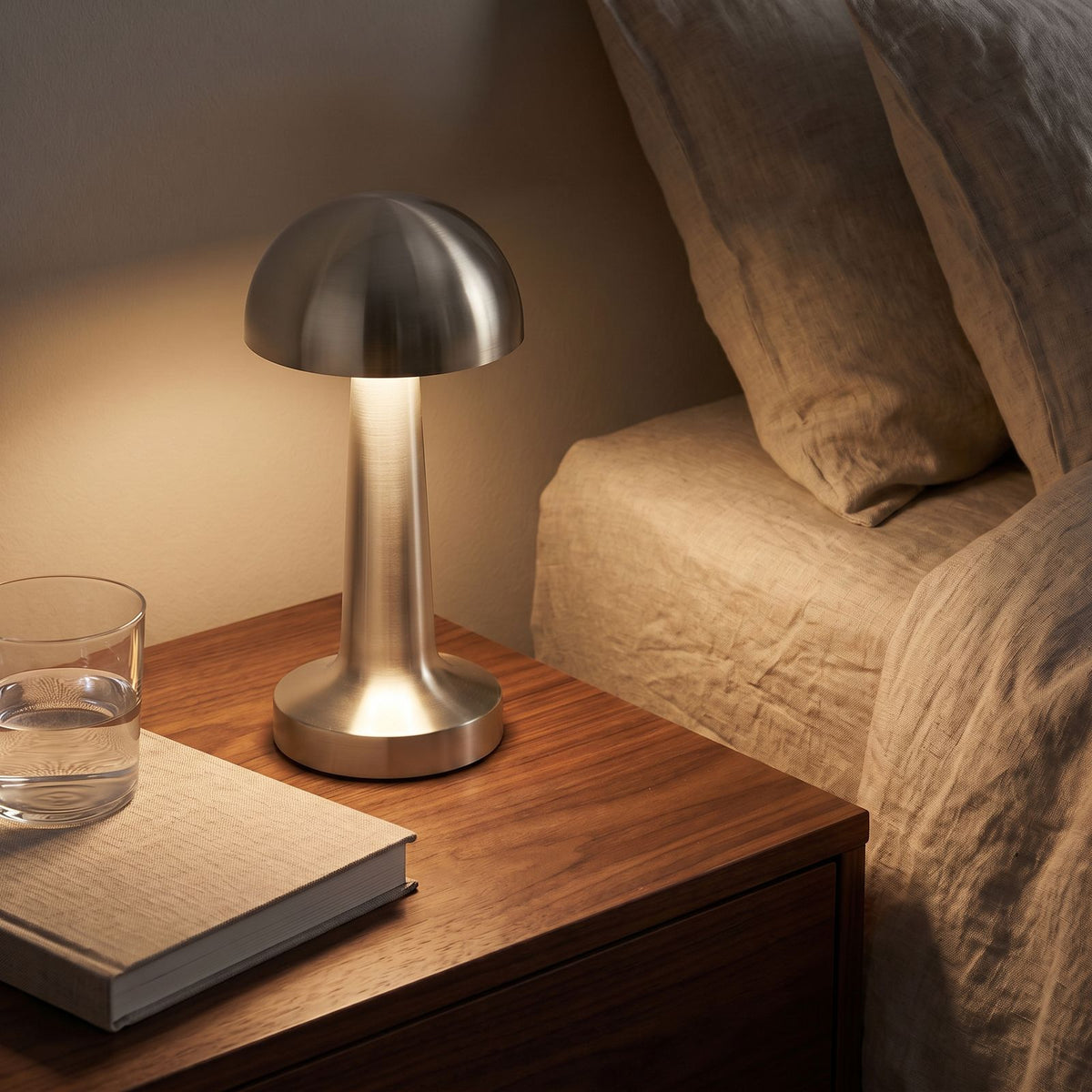 Mushroom Dome Metal Rechargeable Table Lamp in silver on a bedside table