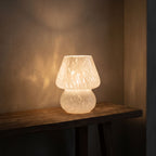 Mushroom Glass Table Lamp glowing on a timber console at night